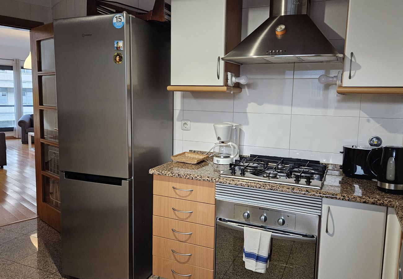 Kitchen with gas stove, oven, stainless steel fridge, and essential appliances.
