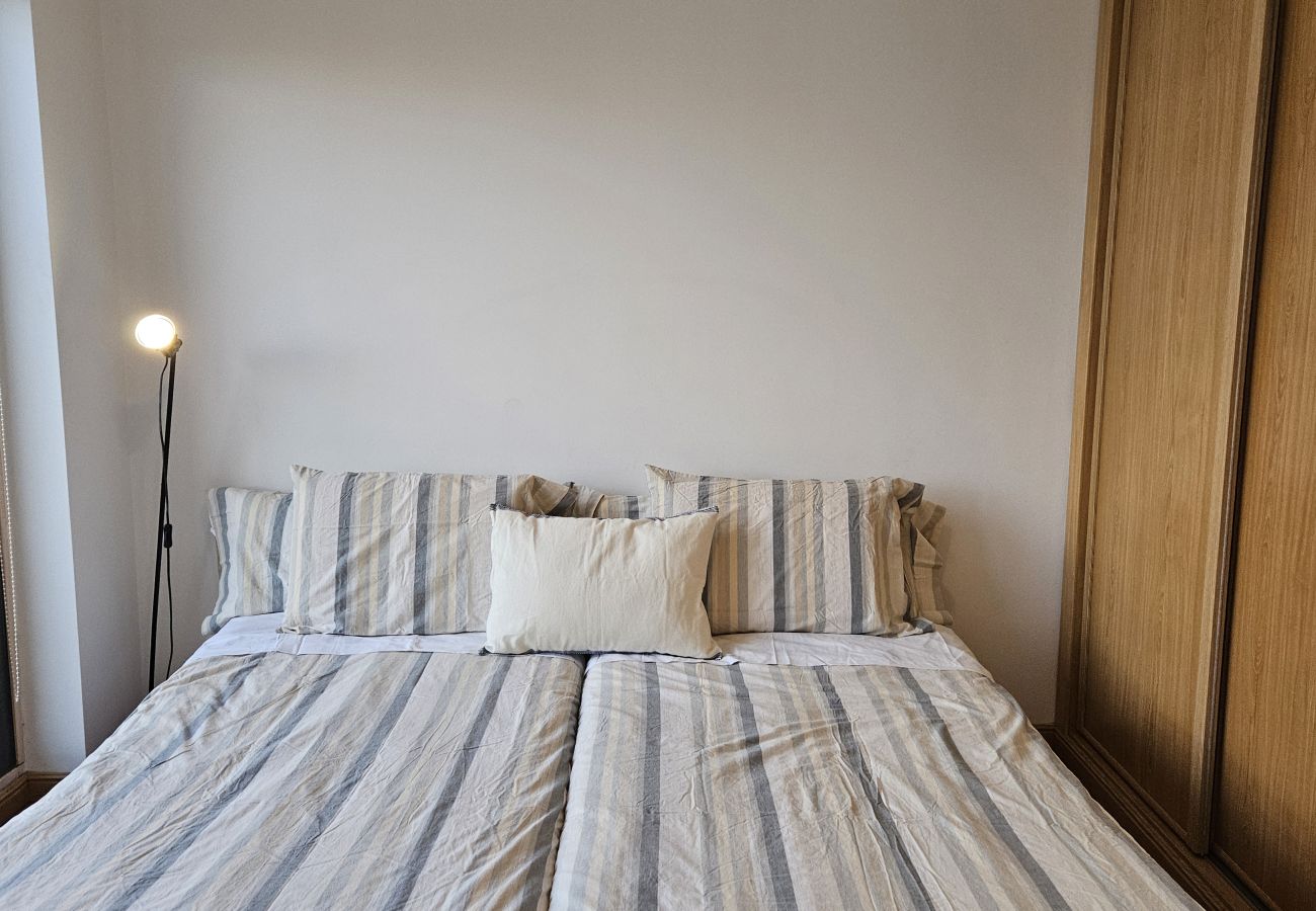Bedroom with a king-size bed, minimalist decor, and large windows with natural light.