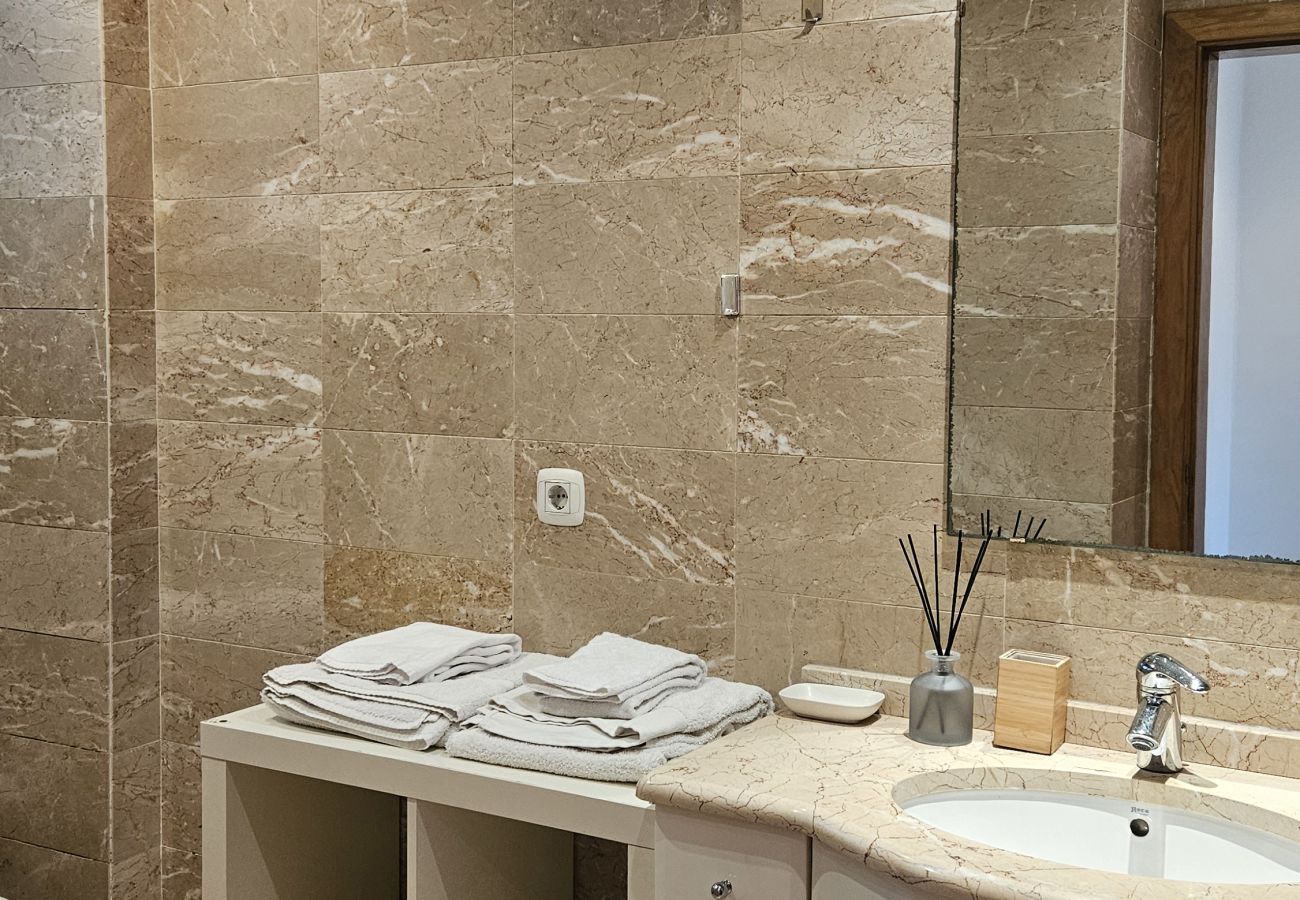 Bathroom with marble walls, large mirror, and white vanity sink.