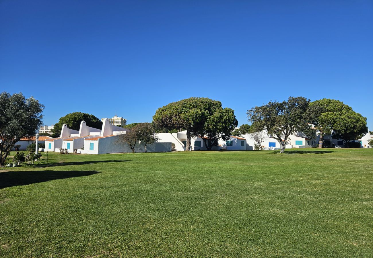 White house exterior with green garden, trees, and blue sky in the background.
