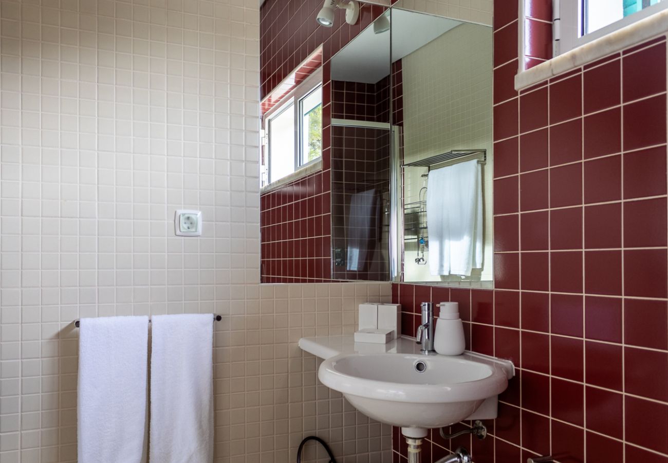 Bathroom with red and white tiles, white towels hanging, and a sink with a mirror.