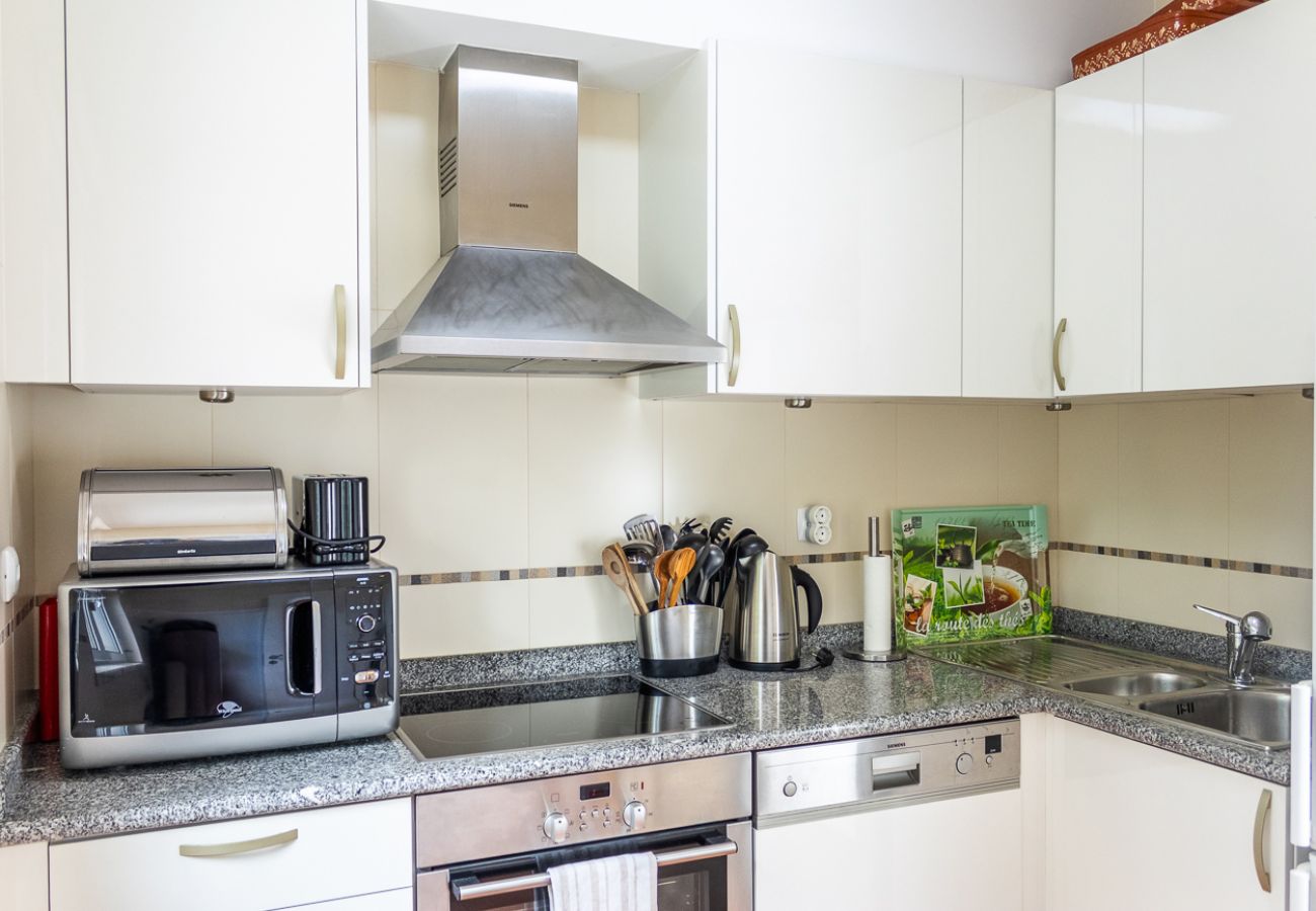 Modern kitchen with white cabinets, appliances, and a granite countertop.