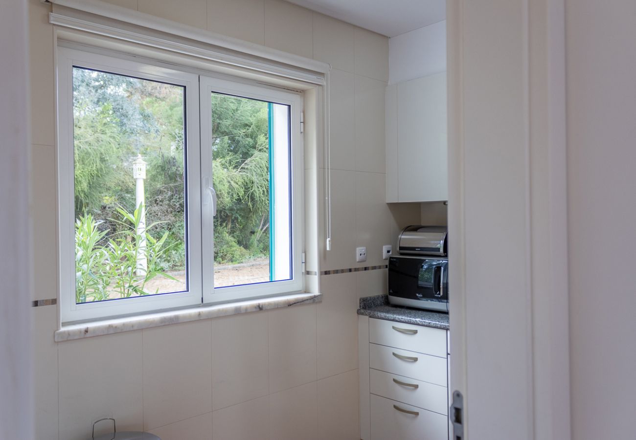Bright kitchen with a large window, garden view, and white cabinets.