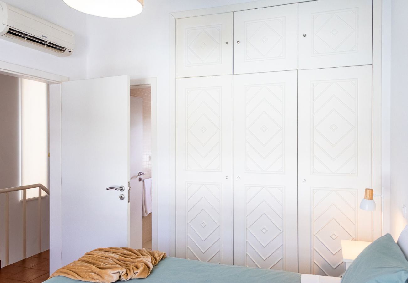 Cozy double bedroom featuring white built-in wardrobes, a neatly made bed, and air conditioning.