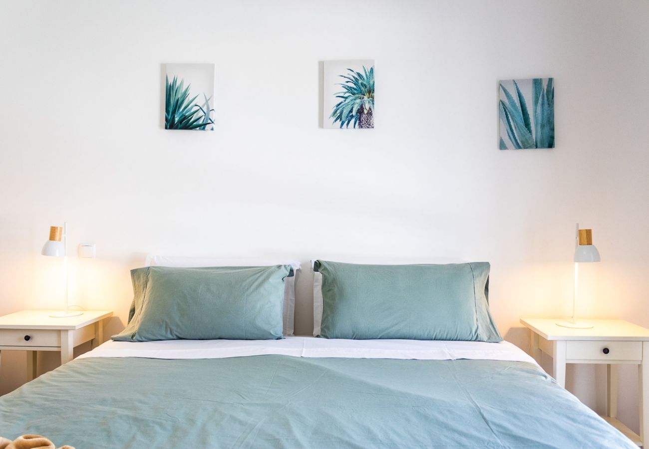 Modern bedroom with a double bed, green bedding, and minimalist wall decor.