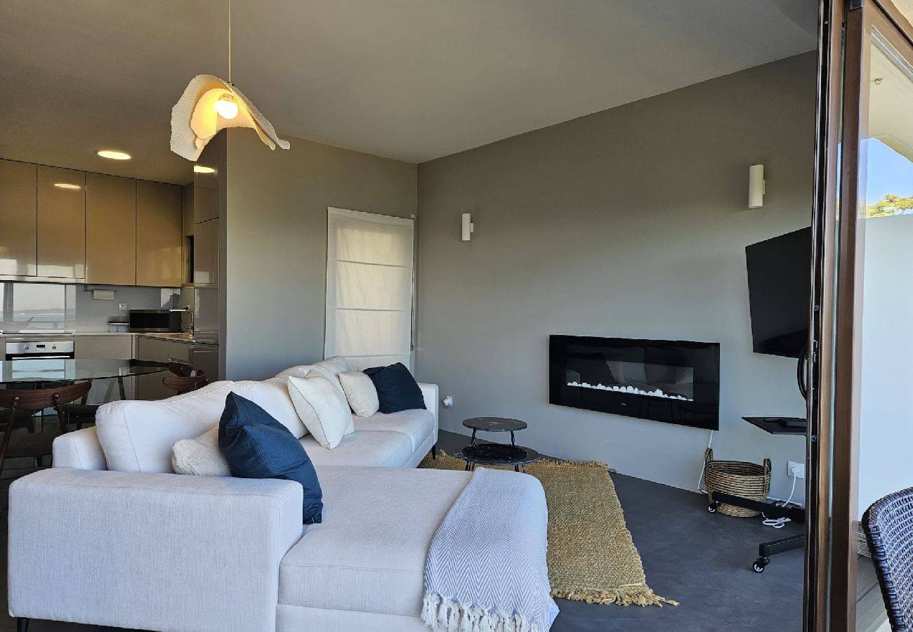 Spacious living room with a large sofa, built-in fireplace, and access to the balcony.