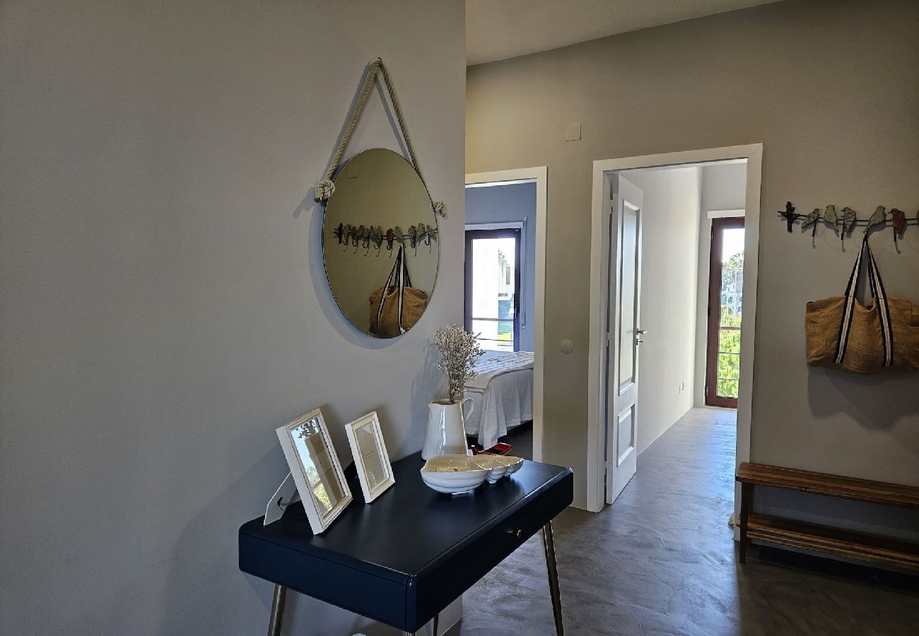 Modern entrance hall with a hanging round mirror, blue decorative table, and open door leading to other rooms.