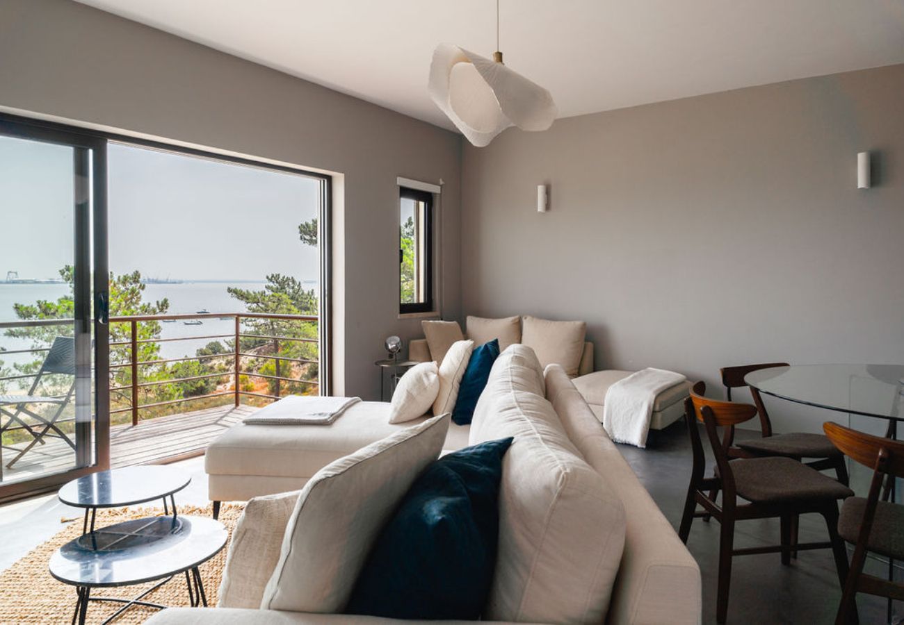 Stylish living room with a large sofa, coffee tables, and a balcony overlooking the ocean.