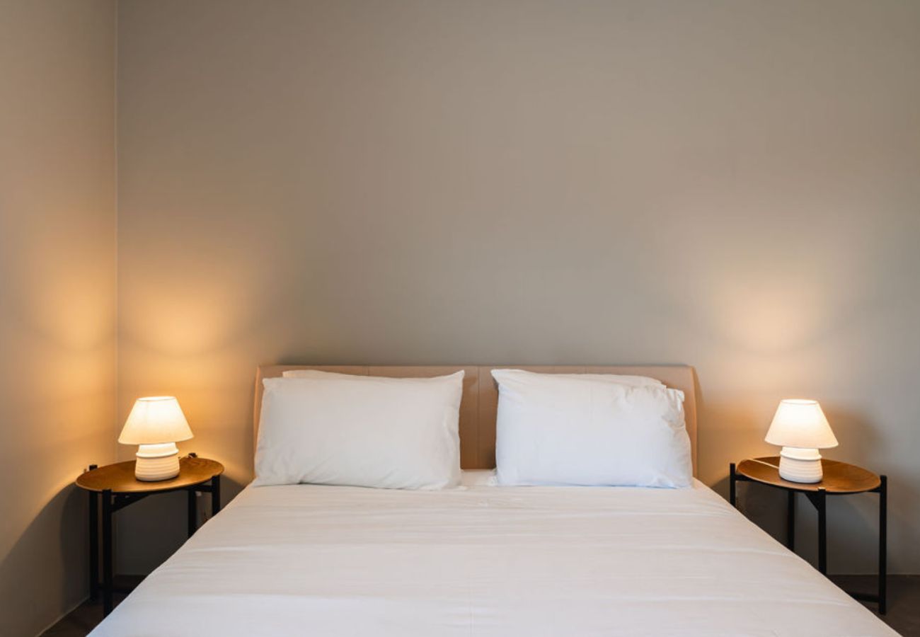 Modern bedroom featuring a double bed, soft bedside lighting, and minimalist decor in neutral tones.