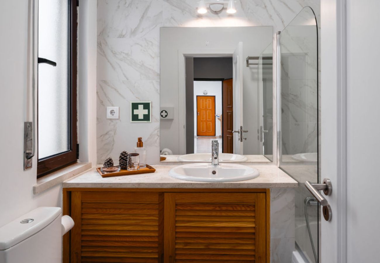 Elegant bathroom featuring a marble sink, large mirror, and slatted wooden cabinet.