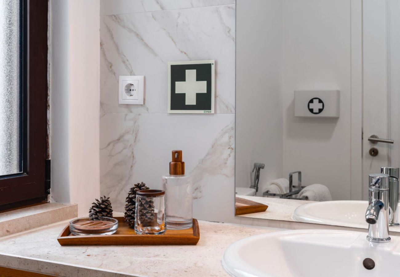  Elegant bathroom sink detail with marble countertop, mirror, and first aid kit on the wall.