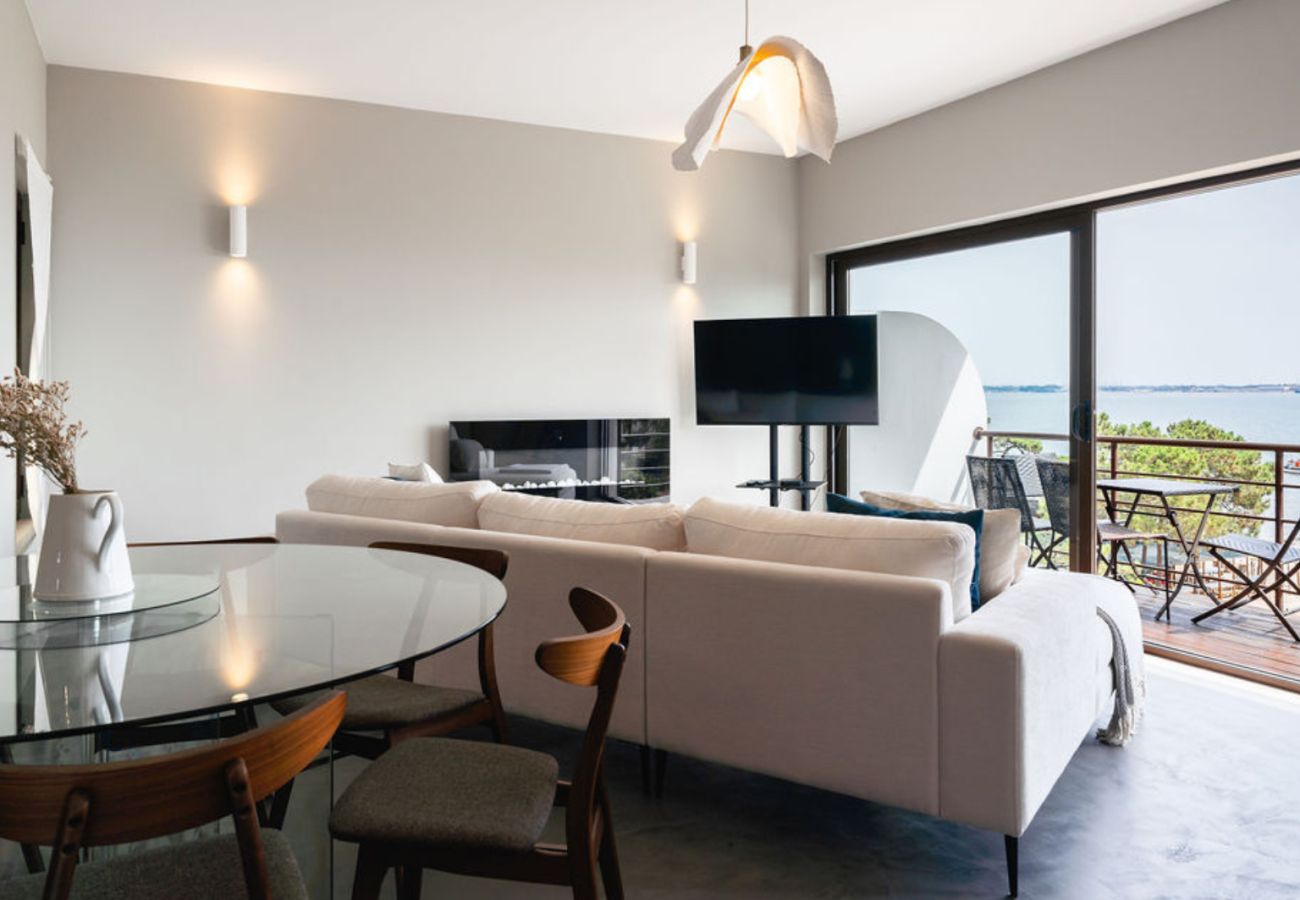 Dining room with a glass table and stylish chairs, integrated with the living room and offering a view of the balcony and sea.
