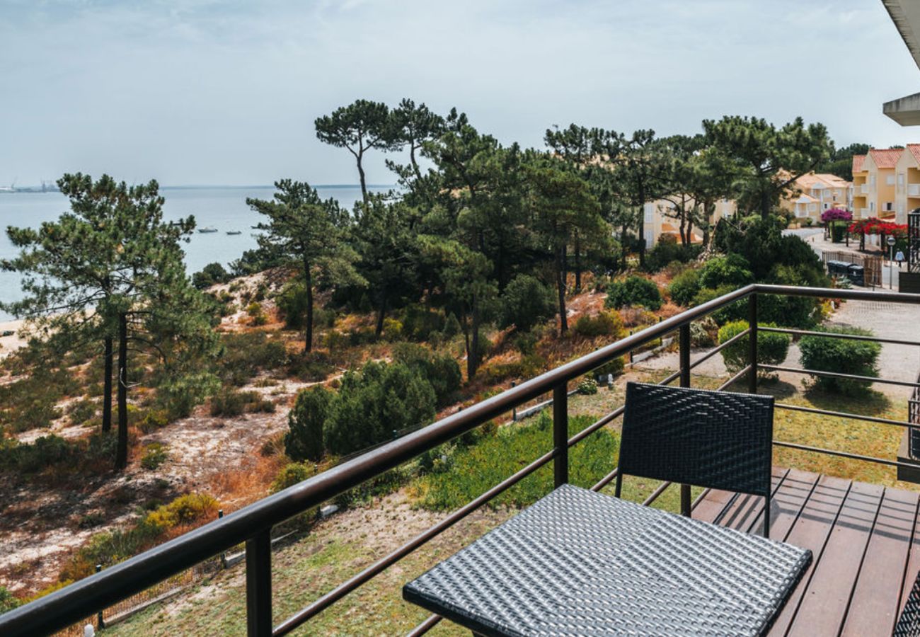 Cozy terrace with table and chairs, overlooking nature, pine trees, and the sea in the distance.
