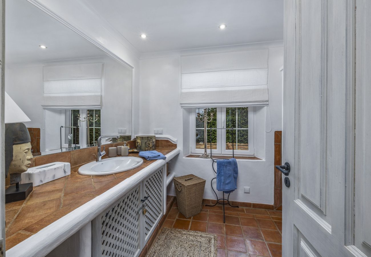Bathroom with double sink, large mirror, and window overlooking the garden, creating a relaxing atmosphere.