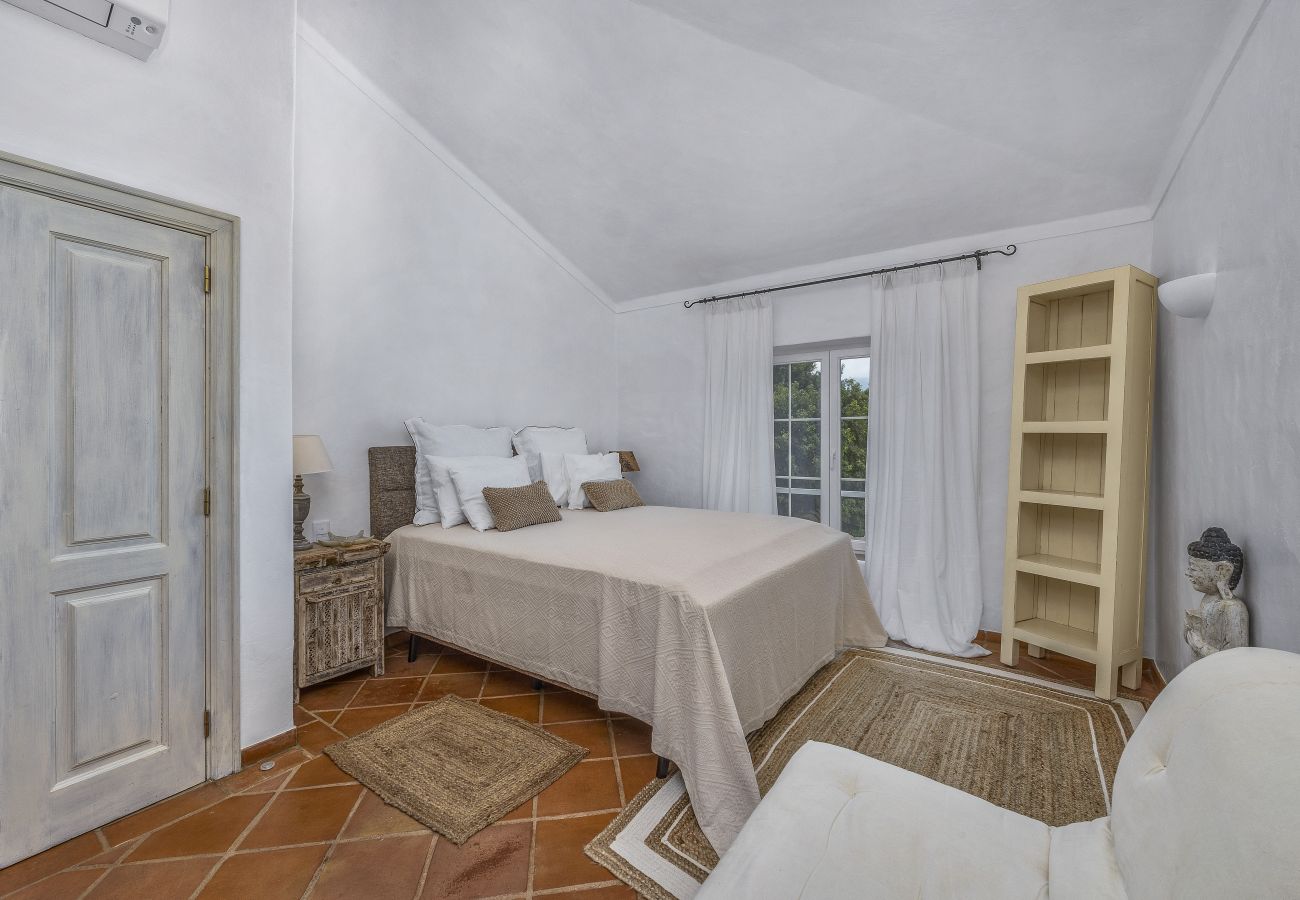  Elegant double bedroom, decorated in neutral tones, featuring rustic furniture and large windows for natural light.