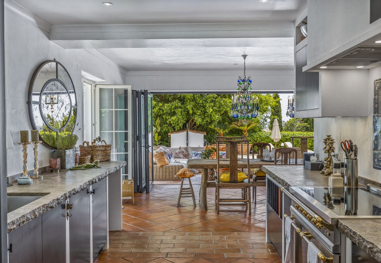 Elegant and spacious kitchen with marble countertops, modern appliances, and an open view of the terrace and lush outdoor area.
