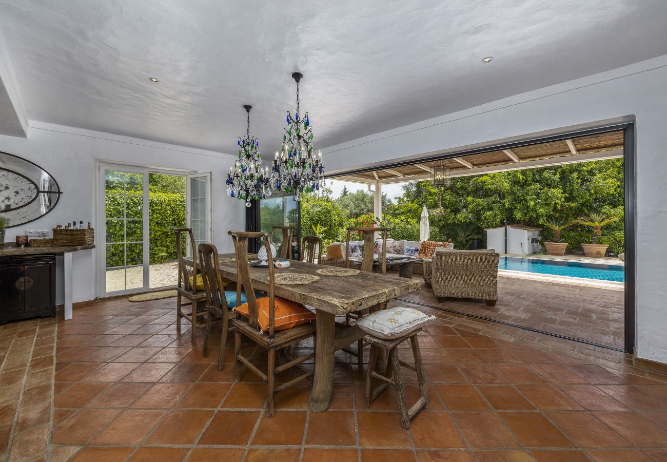 Elegant dining room with a wooden table, vibrant blue chandelier, and garden view.