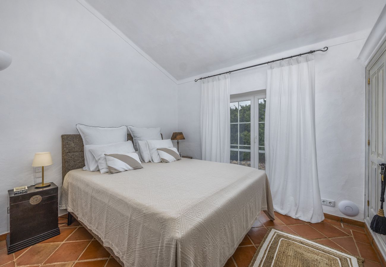 Elegant double bedroom with minimalist decor, comfortable bed, and large windows overlooking the garden.