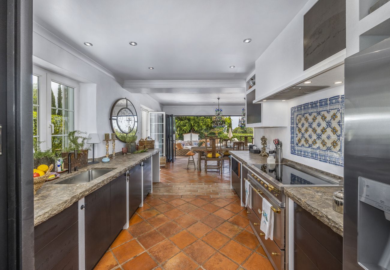 Elegant and spacious kitchen with marble countertops, modern appliances, and an open view of the terrace and lush outdoor area.