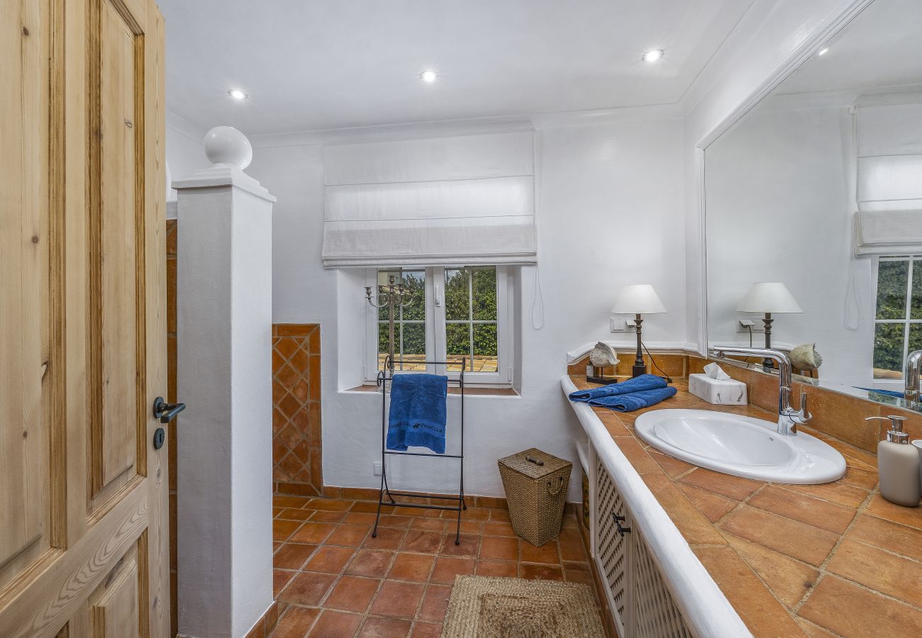 Spacious bathroom with rustic decor, double sinks, large mirror, and windows allowing natural light in.