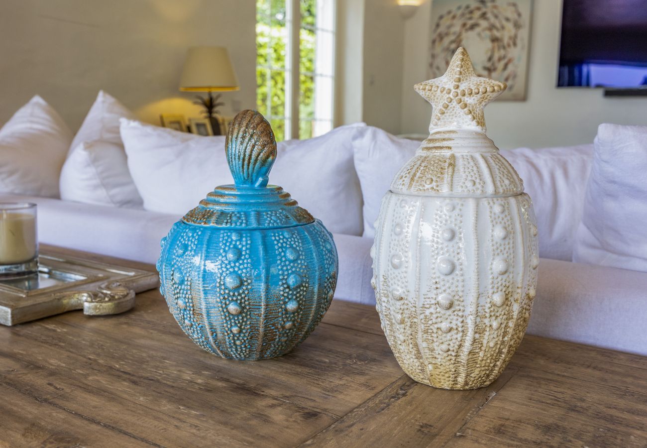 Two ornamental vases, one blue and one white, with textured details inspired by the sea, placed on a wooden table in the living room.