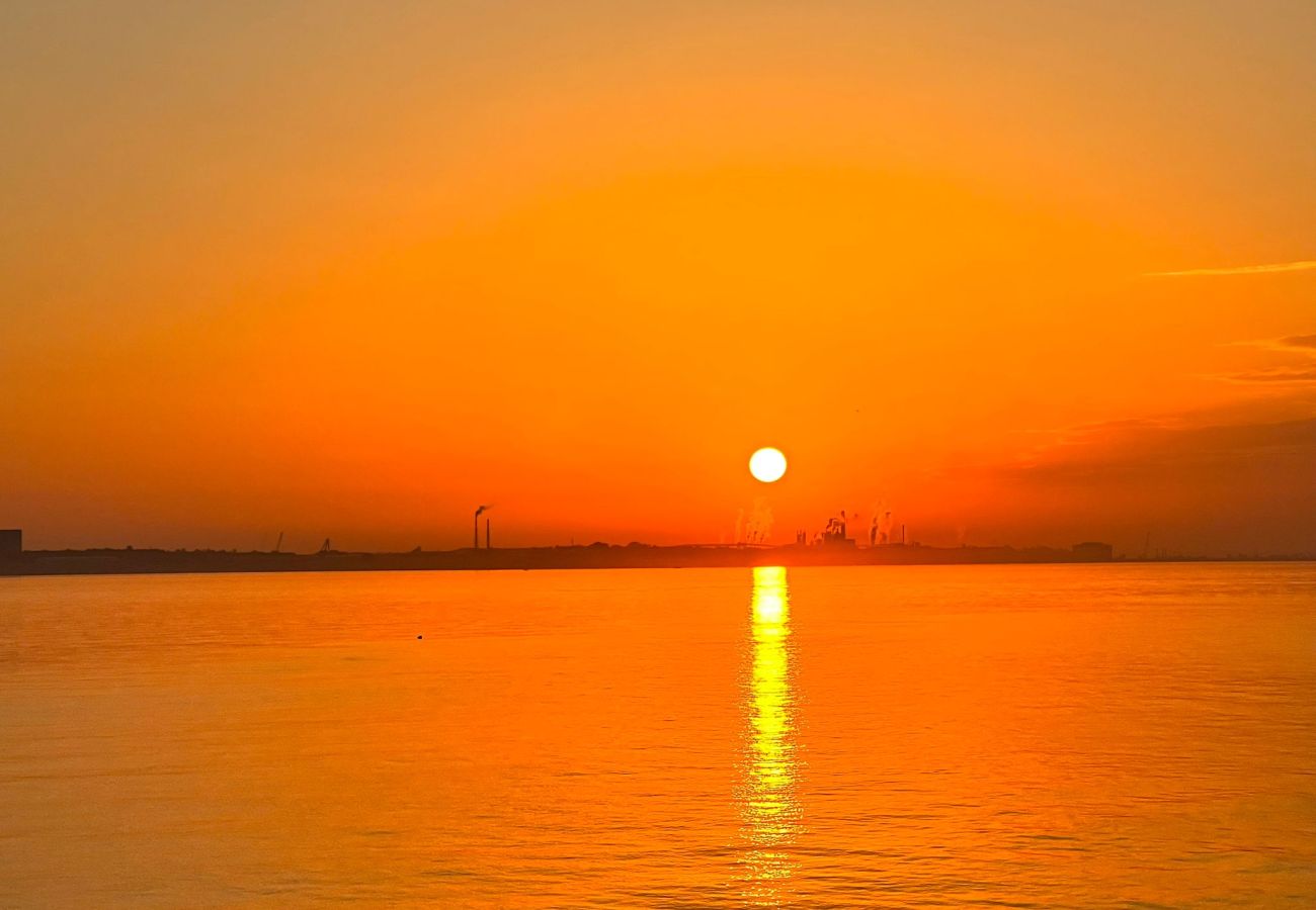 Spectacular view of the sun setting, painting the sky orange and reflecting on the sea