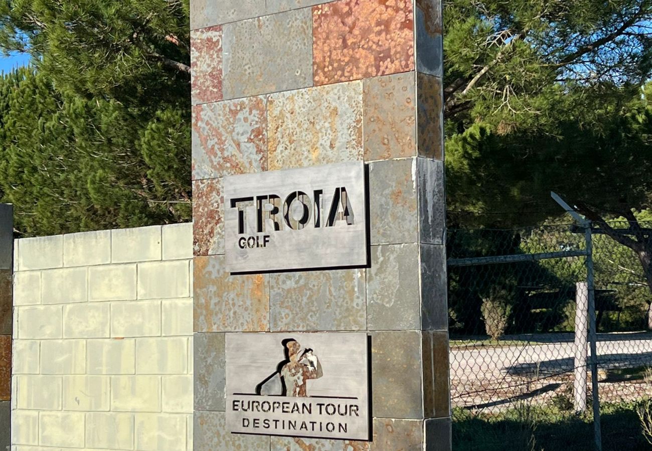 View of the entrance to the golf course in Troia, surrounded by lush vegetation and harmonious architecture.
