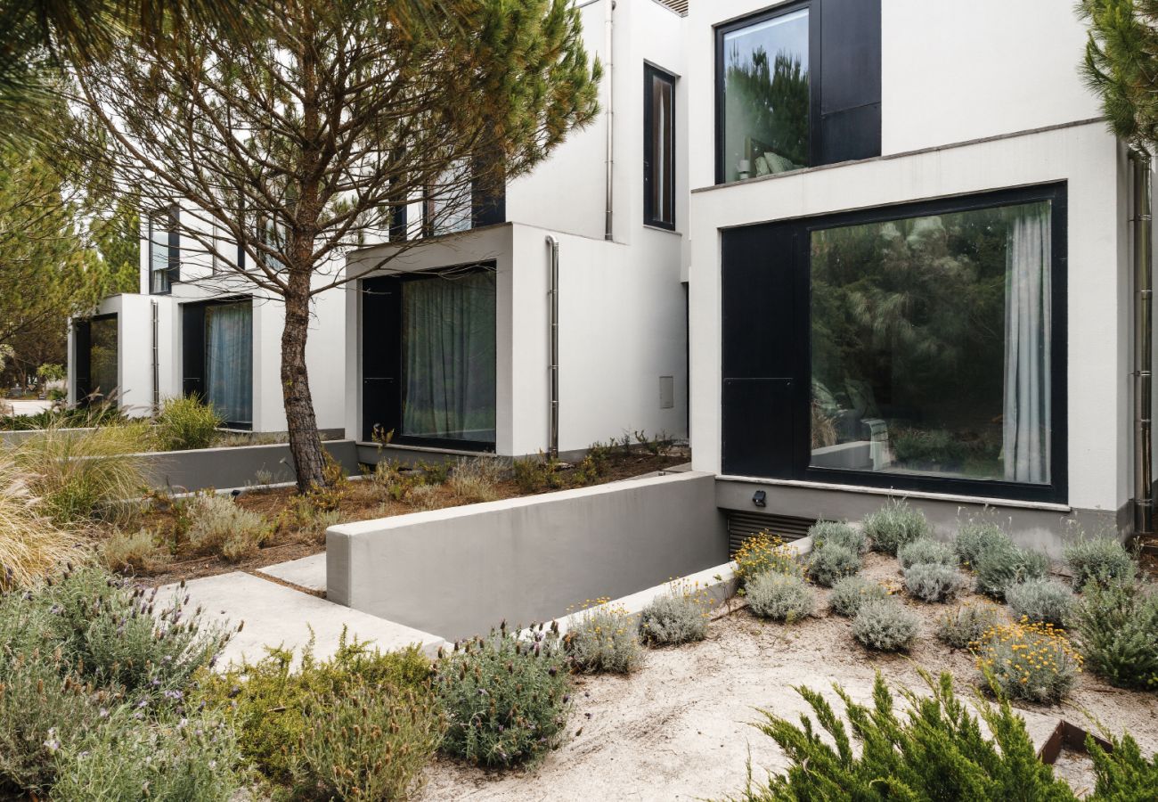 View of the modern facade with large windows and a natural garden blending into the surroundings.