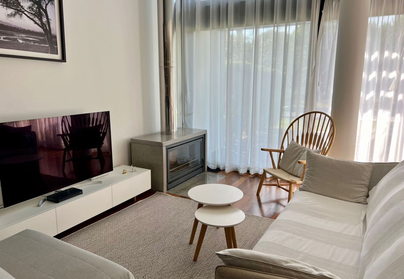 Living room with a comfortable sofa, TV, fireplace, and large windows with sheer curtains, creating a bright and elegant space.