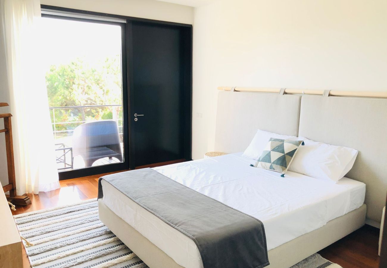 Bedroom with a double bed, upholstered headboard, and modern decor, featuring access to a bright balcony.