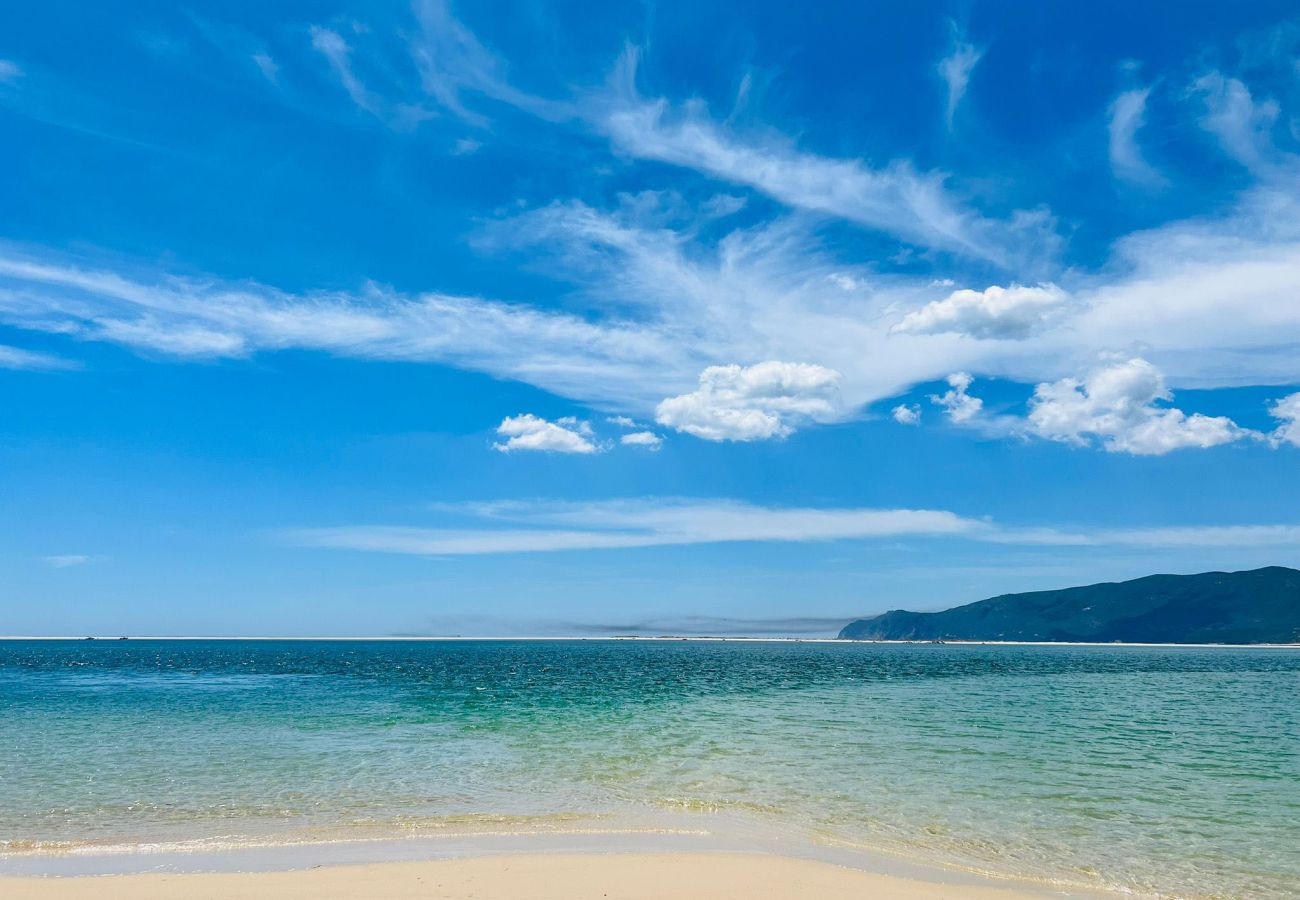  Panoramic view of Troia Beach with golden sands and blue sea under a sunny sky.