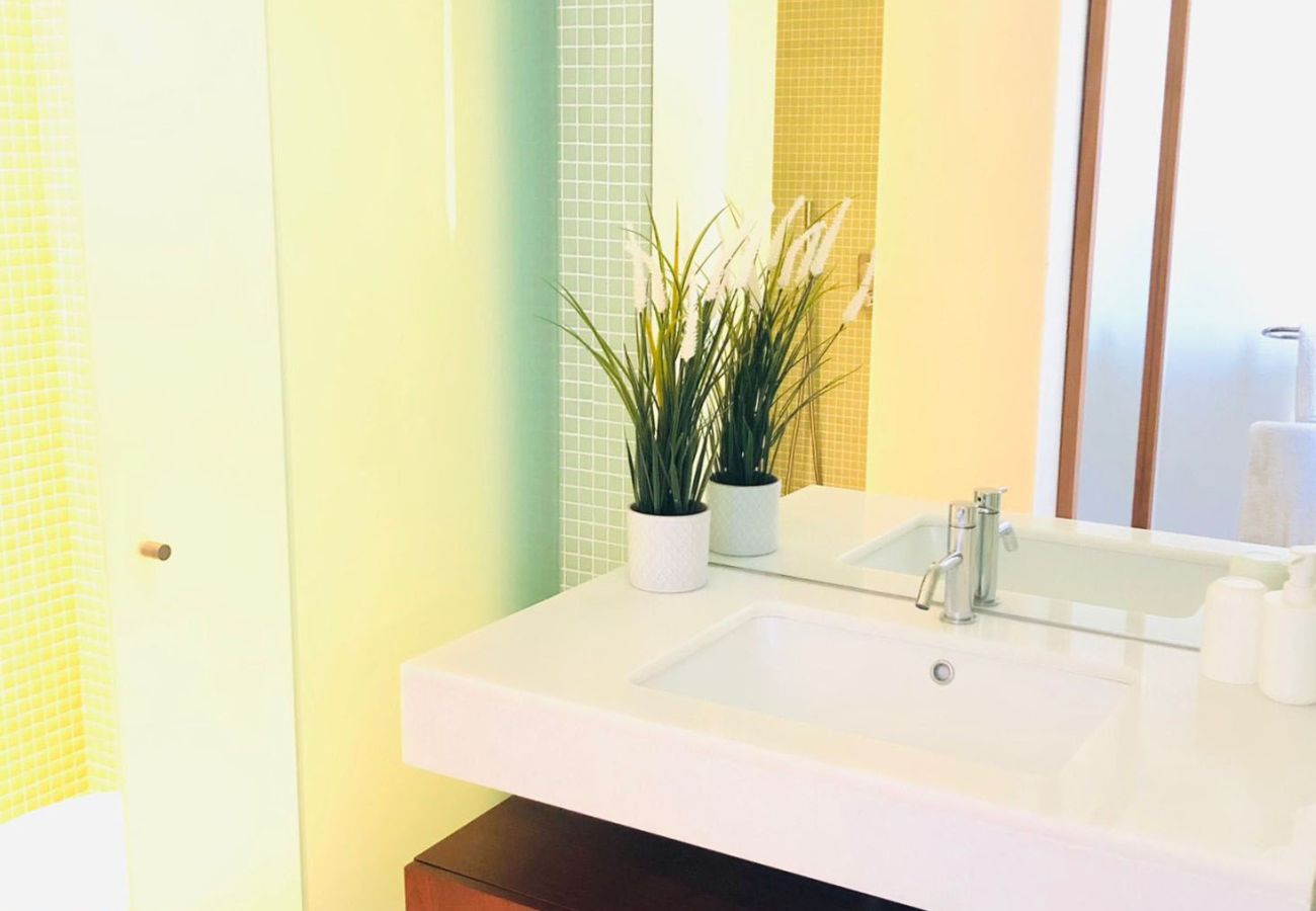 Modern washbasin with a large mirror, wooden cabinet, and elegant details.