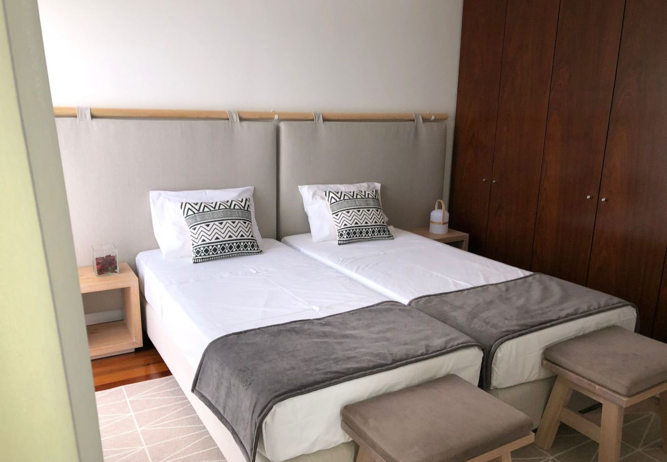 Bedroom with two single beds, upholstered headboard, and built-in wooden wardrobe.