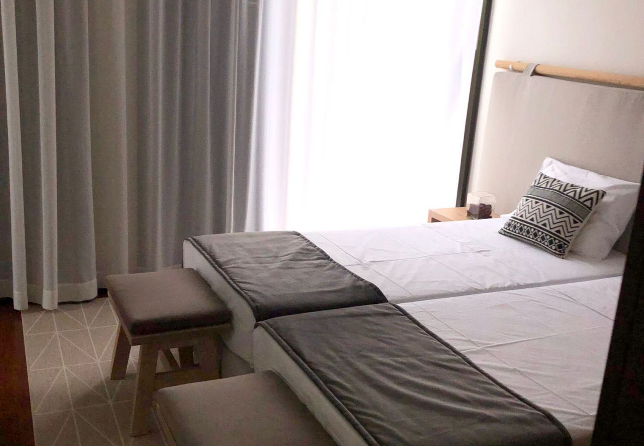 Bedroom with two single beds, elegant decor, and long curtains covering the window.