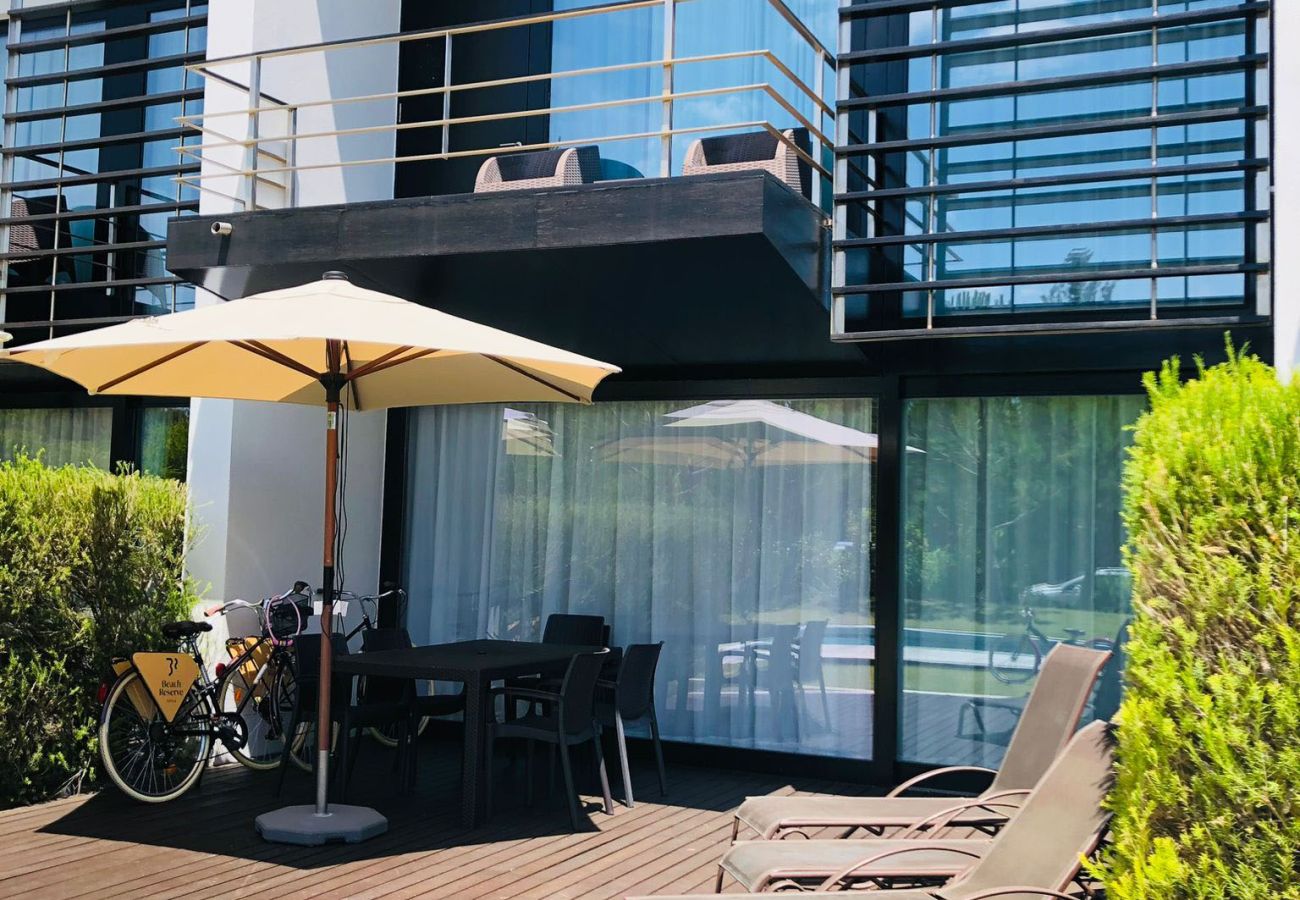Elegant terrace with comfortable sun loungers, an outdoor dining table, and a sunshade for relaxing moments.