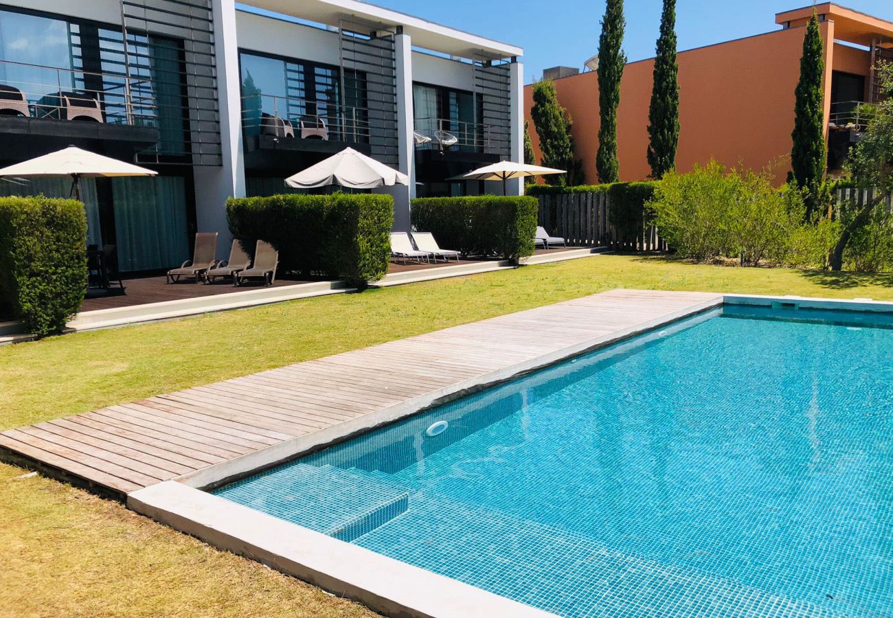 Crystal-clear swimming pool with a wooden deck, surrounded by comfortable sun loungers and a beautiful garden.