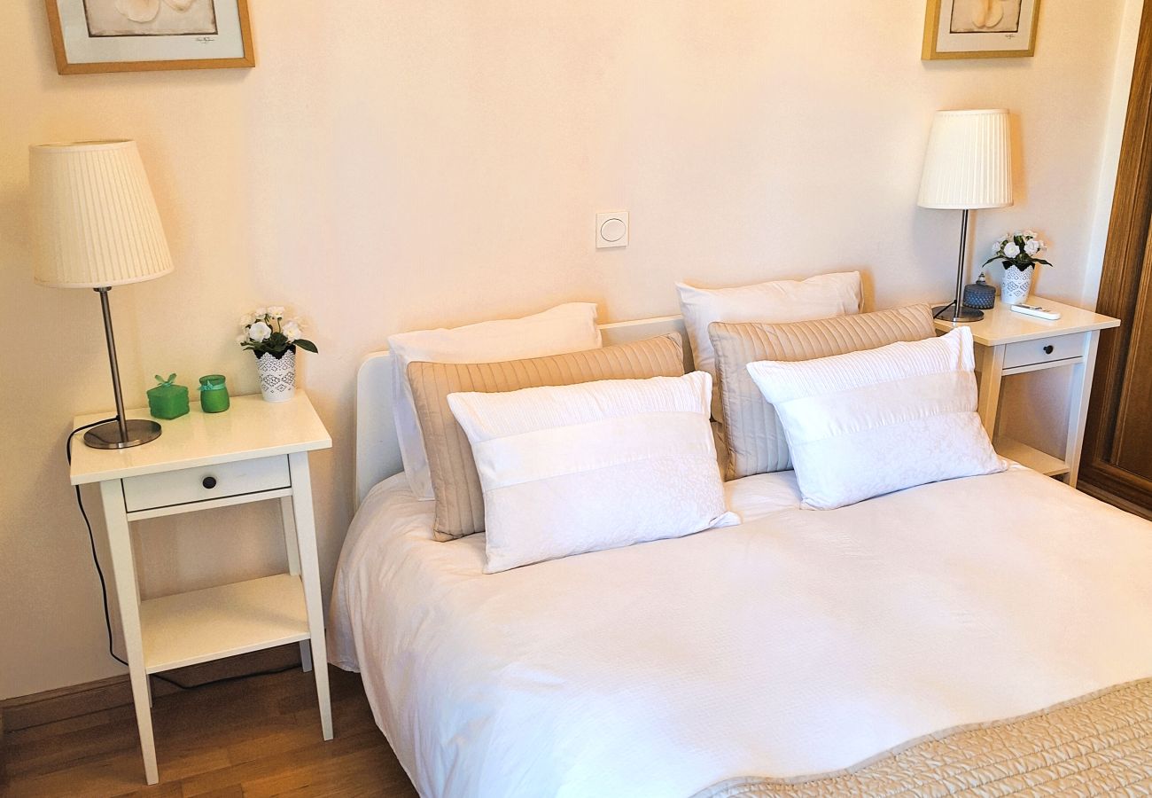 Elegant double bedroom with minimalist decor, a comfortable bed, bedside table, and warm lighting.