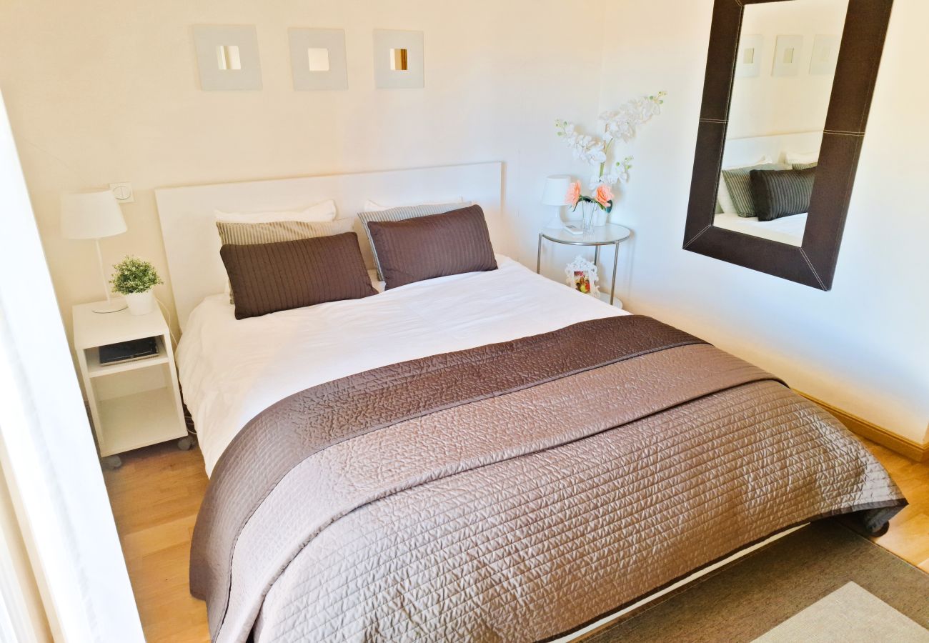 Master bedroom with a double bed, neutral-toned bedding, modern decor, and a large wall mirror.