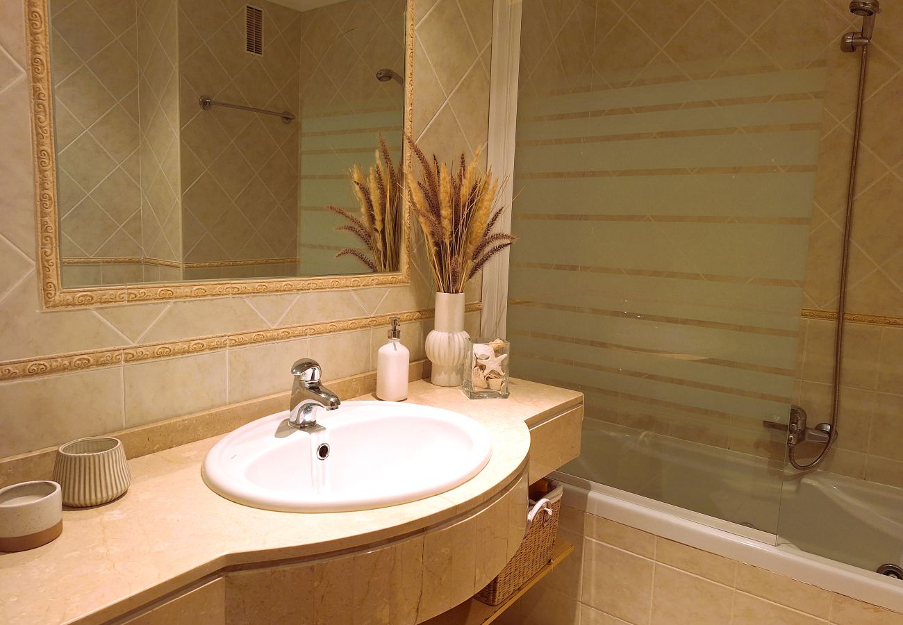 Bathroom with countertop sink, large mirror, bathtub with decorative glass, and sophisticated decor.