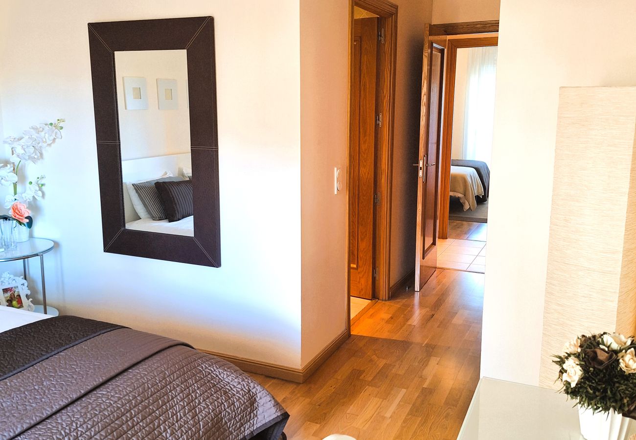 Elegant master bedroom with a double bed, brown bedding, wall mirror, and modern decorative details.