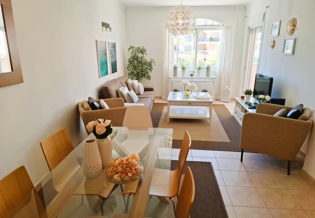 Living room decorated in neutral tones, featuring a comfortable sofa, coffee table, and large windows overlooking the garden.