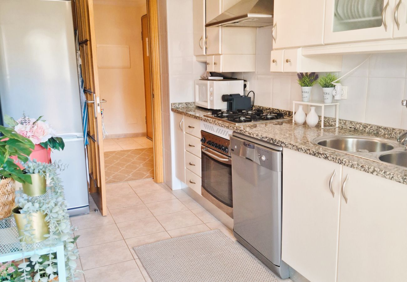 Fully equipped kitchen with white cabinets, granite countertop, modern appliances, and a cozy decoration.