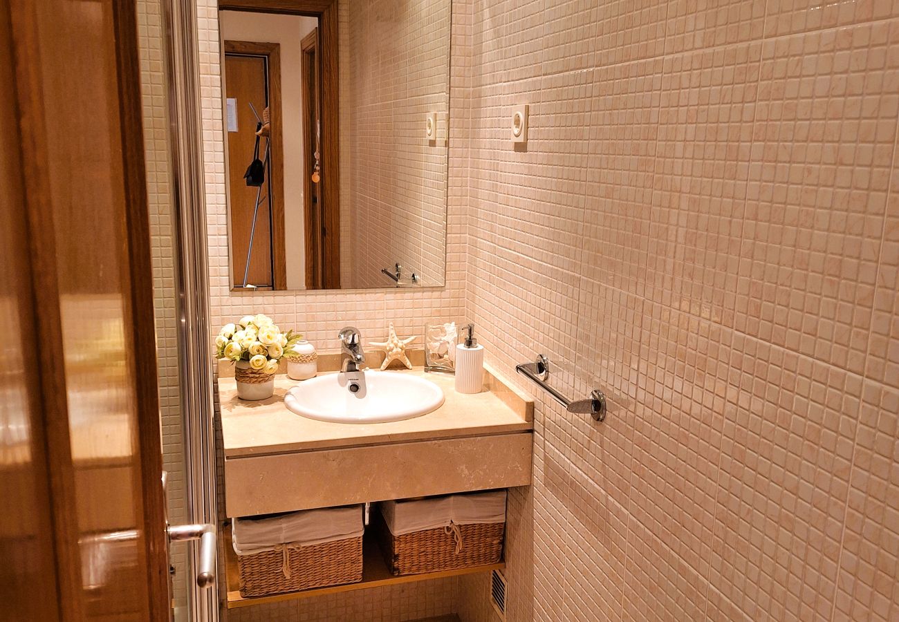 View of the bathroom with mosaic-tiled walls, a large mirror, and an elegant sink with built-in storage.