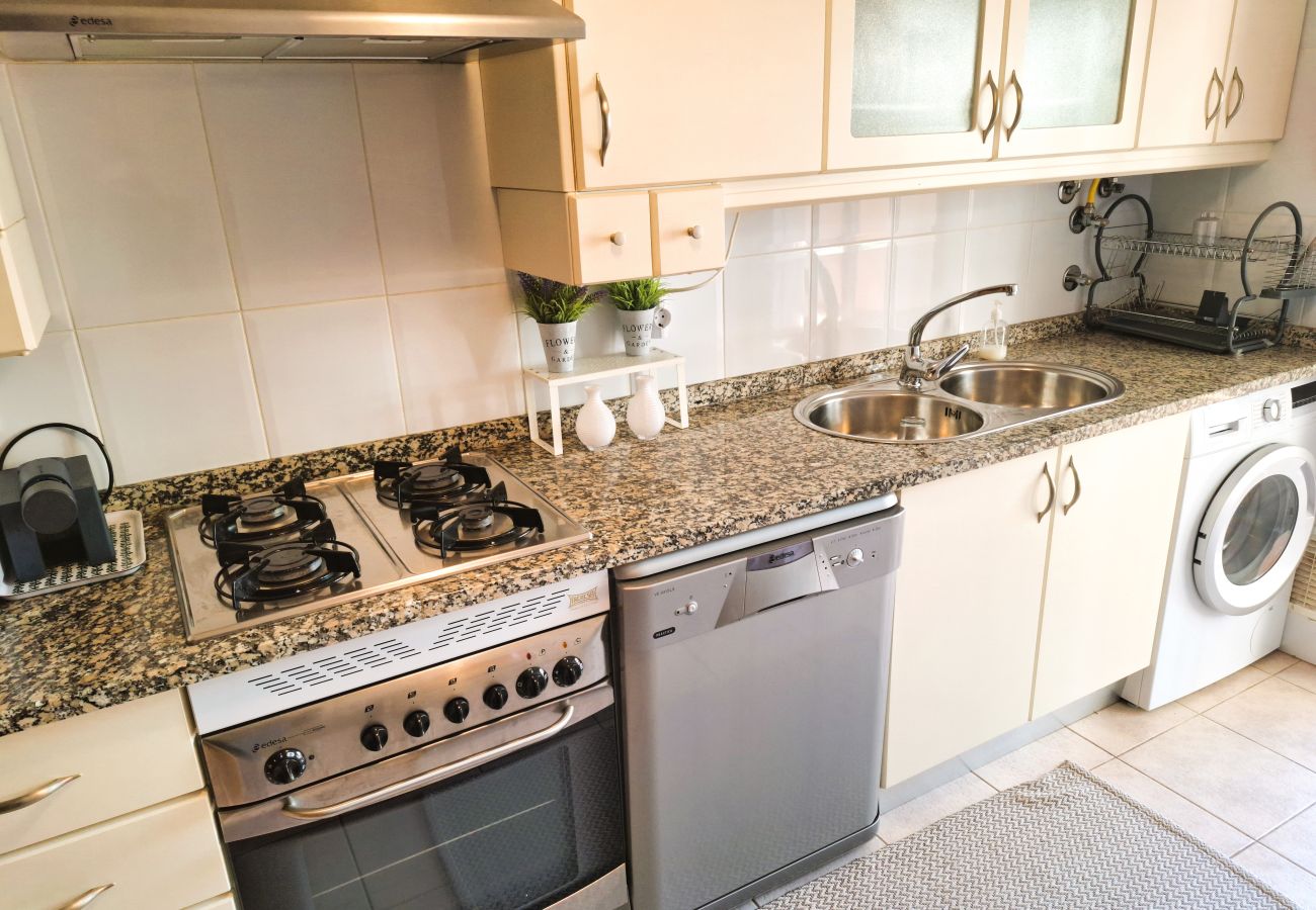 Functional kitchen featuring a stove, oven, dishwasher, and washing machine, along with spacious cabinets and a double sink.