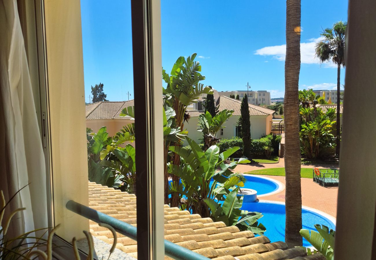Open window with a view of the pool, surrounded by tropical gardens and elegant architecture.