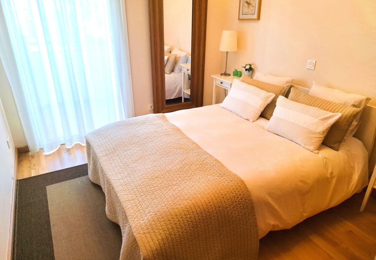 Double bedroom with a comfortable bed, large mirror, white curtains, and a soft, cozy decor.