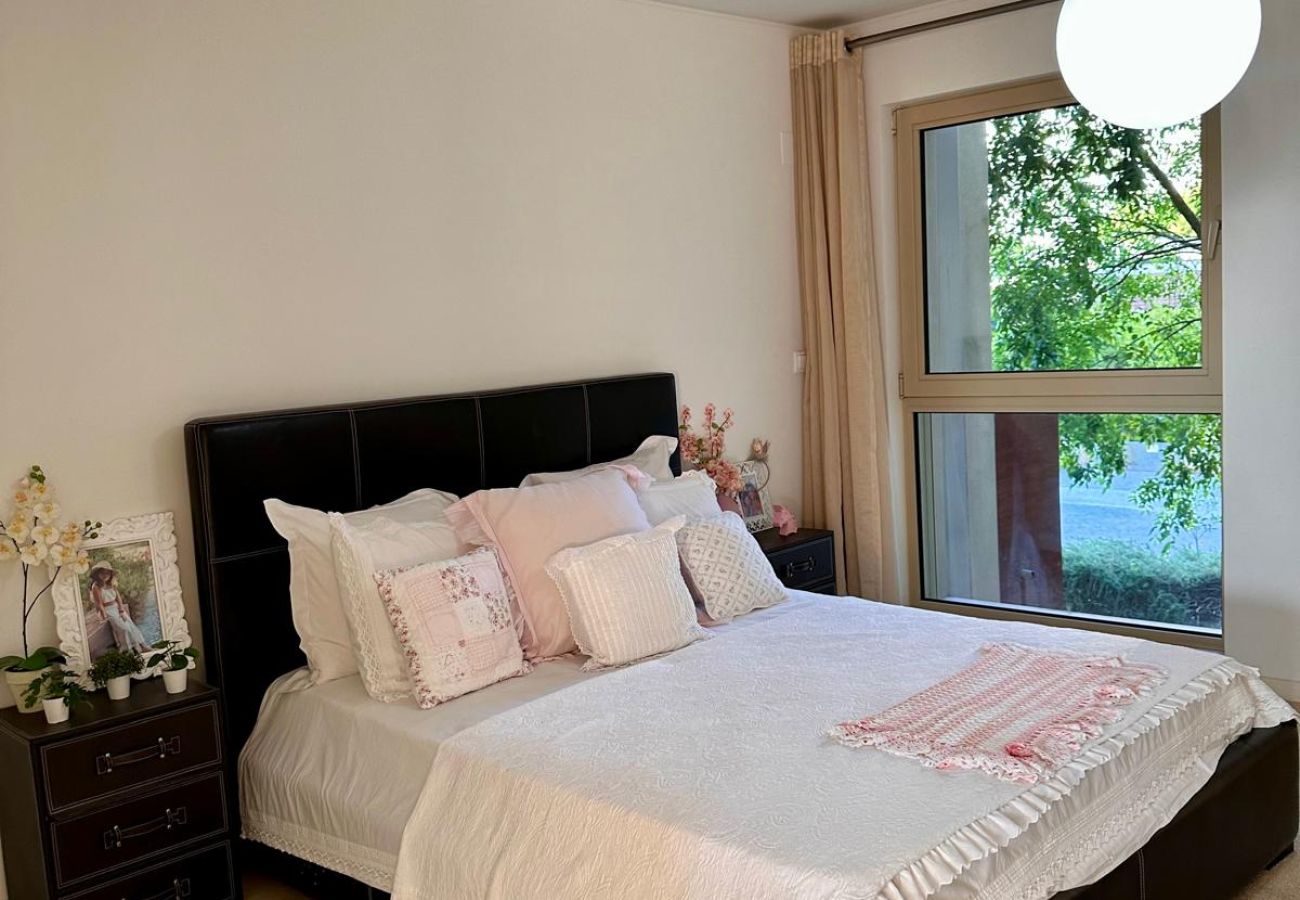 Comfortable and elegant bedroom with a double bed, black upholstered headboard, and white bedding with delicate details. Well-lit space featuring a mo