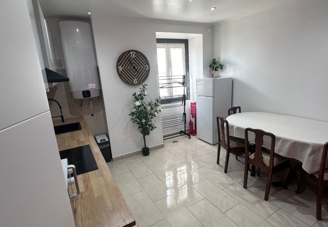 Modern kitchen with white cabinets, wooden countertop, and dining room with a large table and chairs.