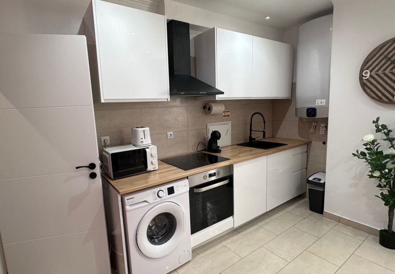 Functional kitchen featuring white cabinets, built-in oven, washing machine, and microwave.