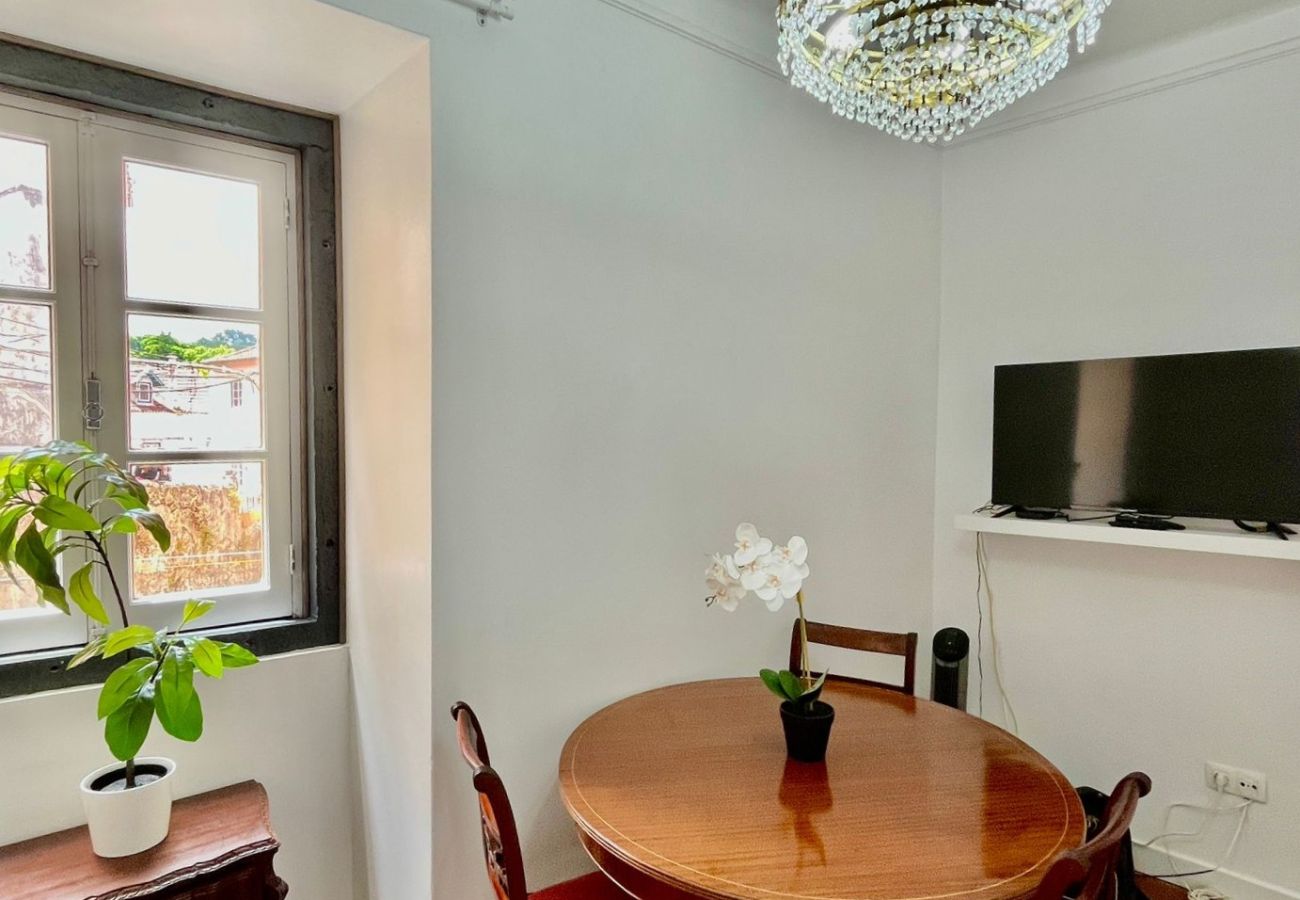  Cozy dining room with wooden table, upholstered chairs, TV, and crystal chandelier.